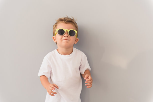 小男孩戴着太阳镜在摄影棚里摆姿势图片下载