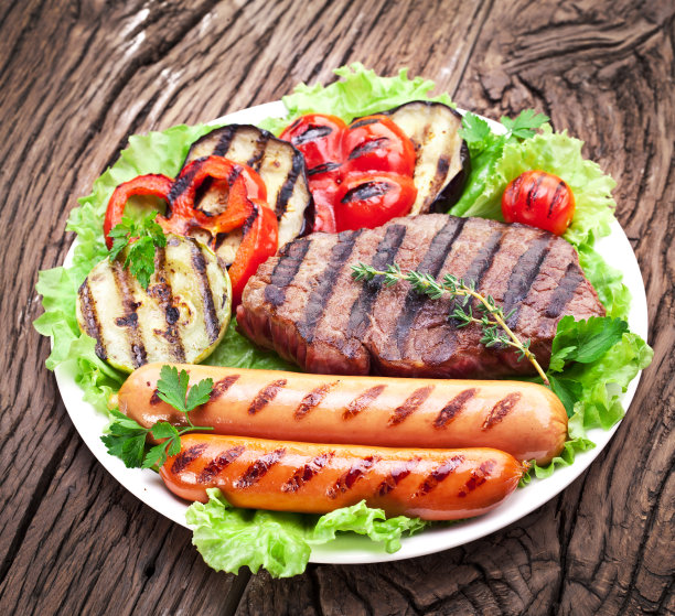 烤牛排，香肠和蔬菜放在生菜叶子上。图片下载