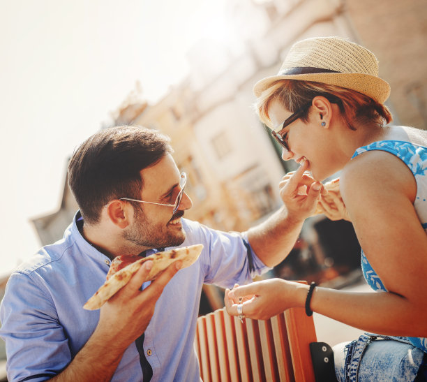 一对情侣在户外吃披萨，面带微笑图片下载