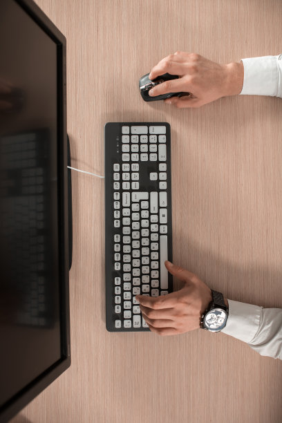 办公室的木桌桌上有电脑和周边设备。图片下载