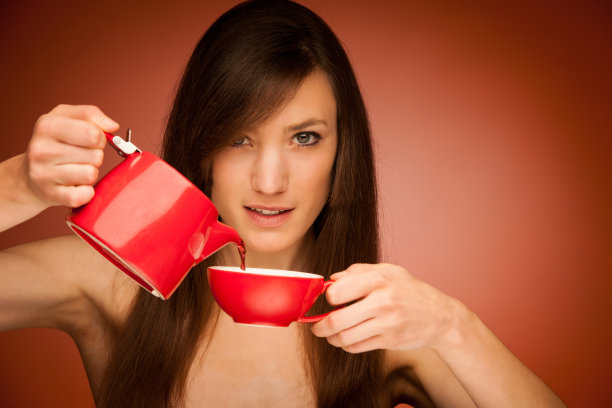 手里拿着茶壶和马克杯的女人图片下载