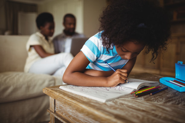 女儿在书上画画，而父母在后台使用笔记本电脑图片下载