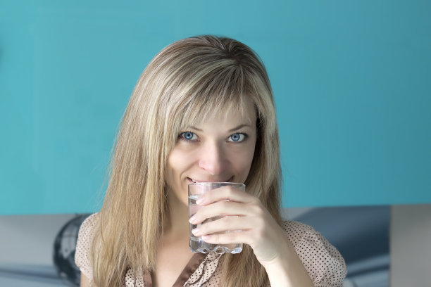 一个年轻女人在厨房喝水的肖像图片下载