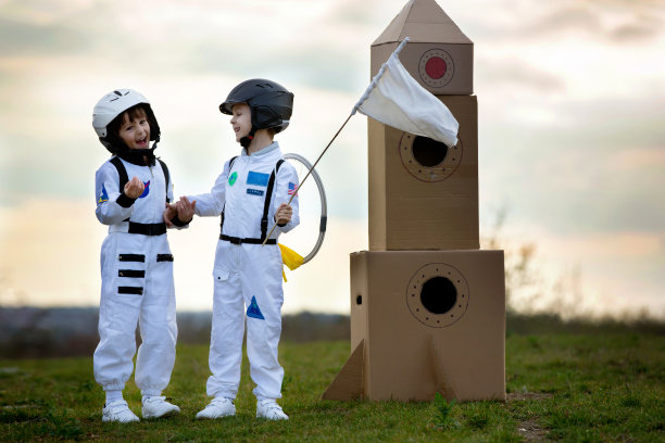 两个可爱的孩子，男孩兄弟，在日落时在公园里玩耍，打扮成宇航员，想象自己在月球上飞行图片下载