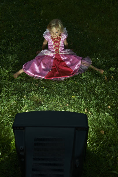 金发小女孩在外面的花园里看电视图片下载