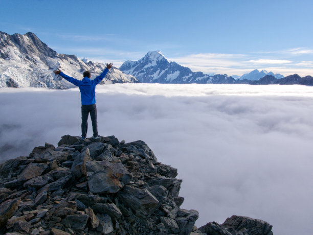 人站在悬崖上越过云看给人印象深刻的山峰图片下载