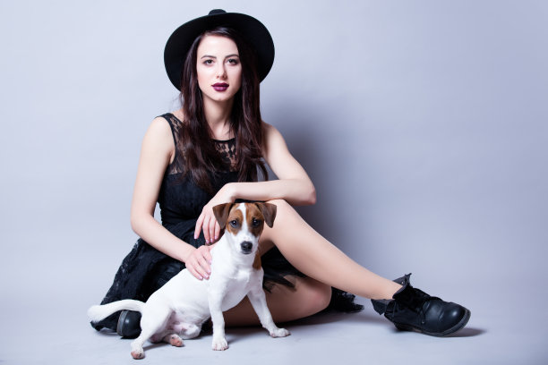 美丽的年轻女子和她的狗坐在美妙的白色工作室背景图片下载