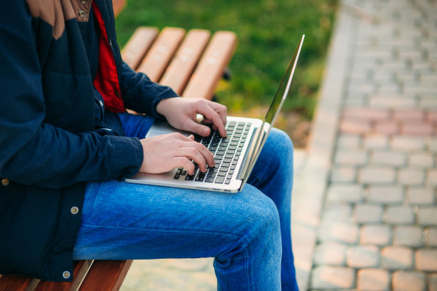 年轻的经理在公园里用笔记本电脑工作。图片下载