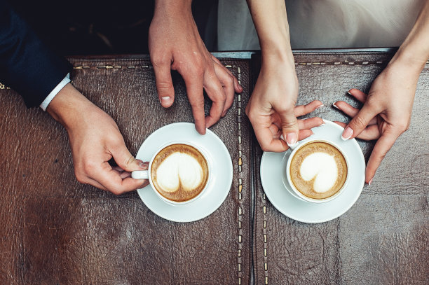 新娘和新郎在咖啡色的木桌旁喝咖啡图片下载