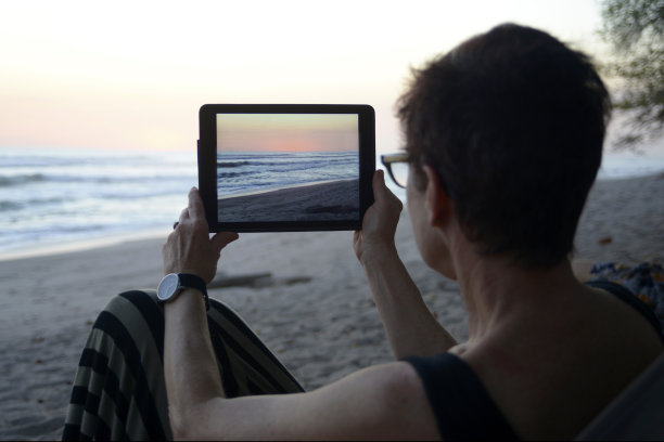 一个女人用平板电脑给海洋拍照图片下载