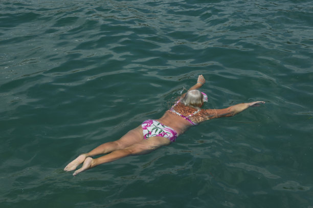 一位老妇人戴着游泳面罩在海里游泳。图片下载