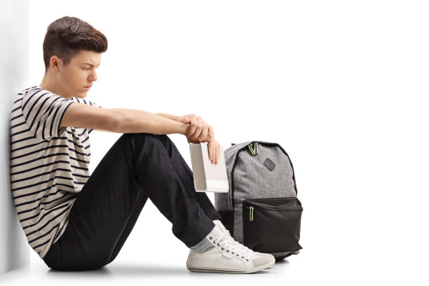 一个靠墙沉思的青少年学生图片下载