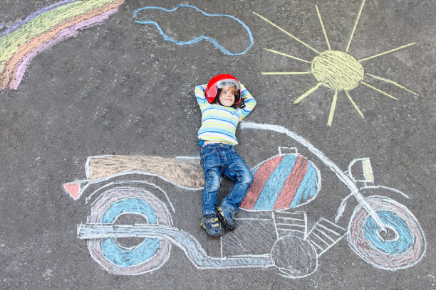 小孩子戴着头盔，骑着摩托车，画着彩色的图画图片下载