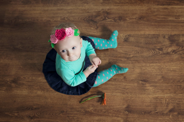 女婴正坐在地板上。图片下载