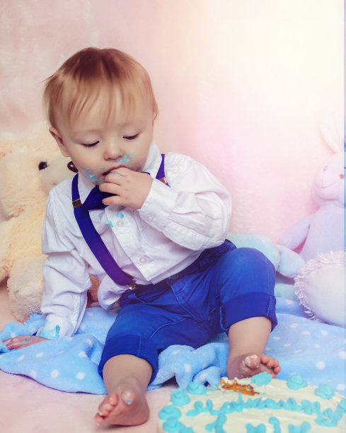 快乐的小男孩在他的第一个生日派对上吃蛋糕图片下载