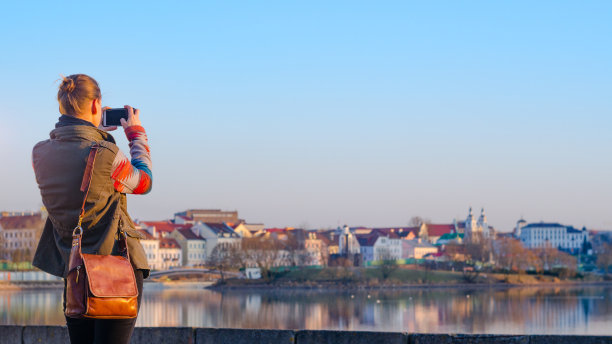 一名年轻女子用智能手机拍摄这座城市的照片图片下载