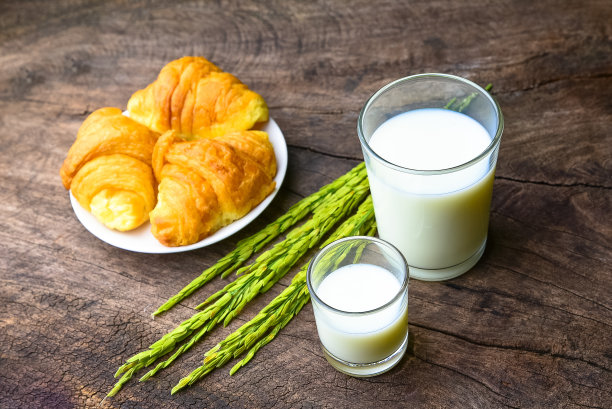 牛角面包配米饭、牛奶和米穗放在旧木桌上作为早餐的背景和素食的概念。图片下载