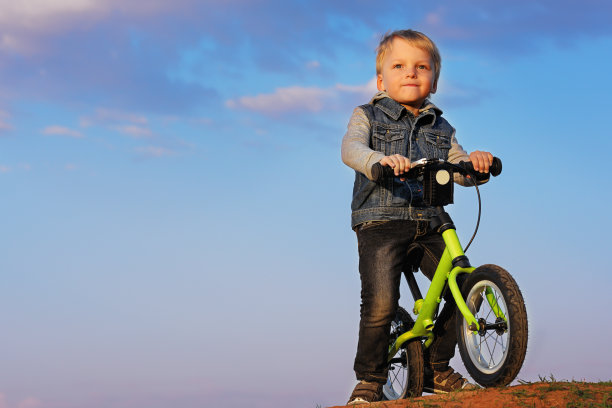 那个男孩骑着自行车，背景是傍晚或早晨的天空。图片下载