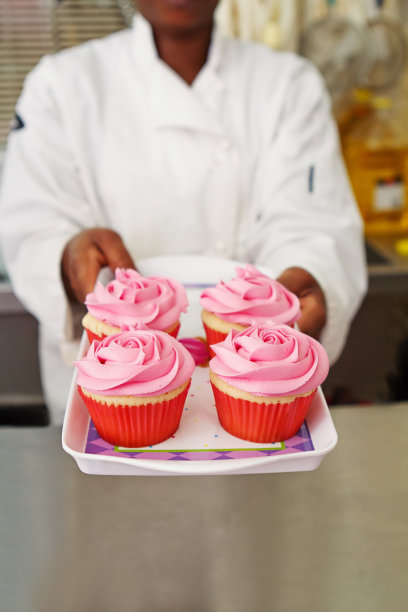 糕点师端上一盘粉色纸杯蛋糕图片下载