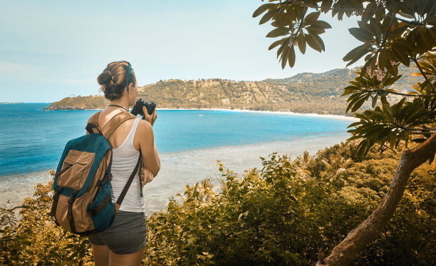 背包旅行者手持望远镜欣赏美丽的海岸景色图片下载