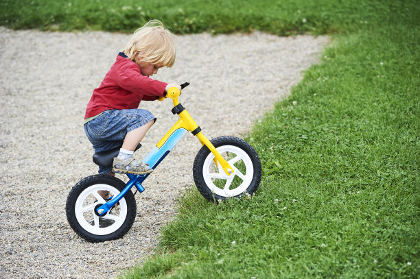快乐的蹒跚学步的男孩骑自行车。喜欢骑自行车的孩子们。图片下载