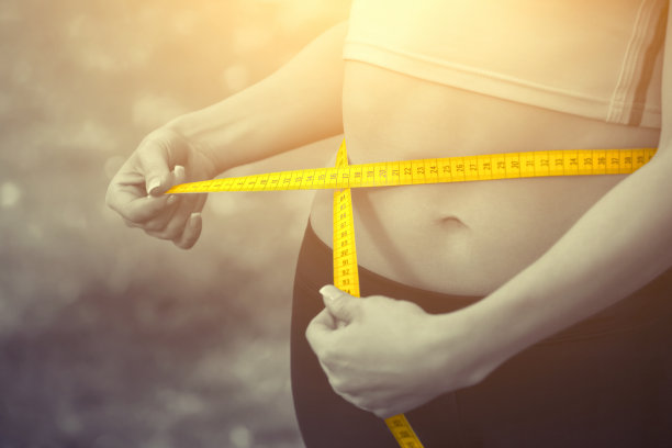 运动女孩用黄色的卷尺测量腰围。减少多余的重量图片下载