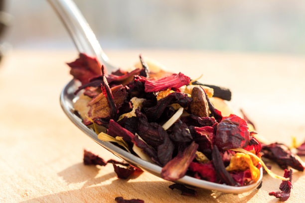 一堆水果茶与花瓣和干果。这堆茶叶和干木槿花的成分位于一块木板上。茶与天然成分特写。茶的微距照片。图片下载