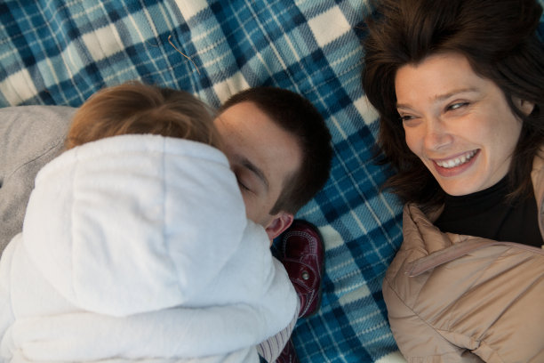 小女儿亲吻睡在毯子上的父亲图片下载