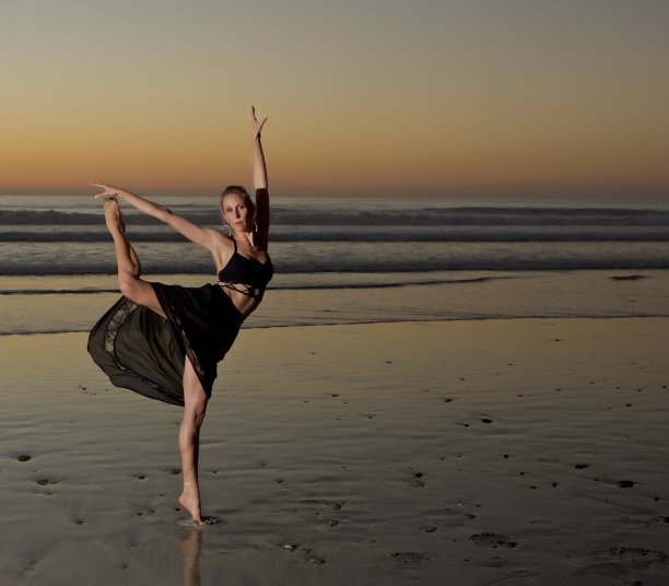 日落时在海滩上练习瑜伽的女人图片下载