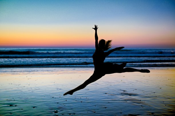 日落时在海滩上跳跃的人图片下载
