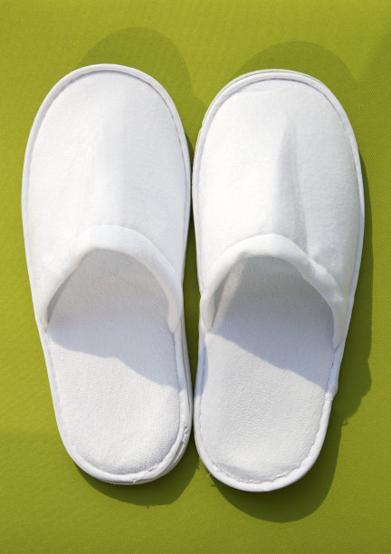 绿色背景下酒店用的白色一次性拖鞋图片下载