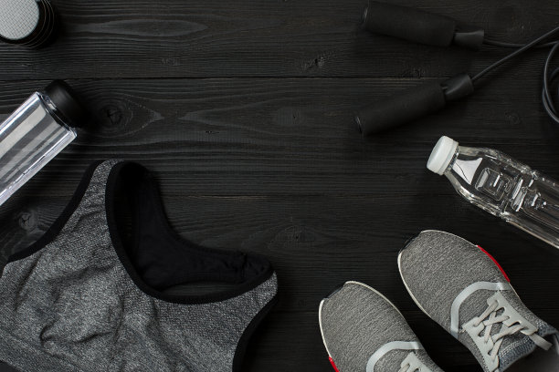 运动员的设置与女性服装，运动鞋和瓶装水在黑暗的背景图片下载