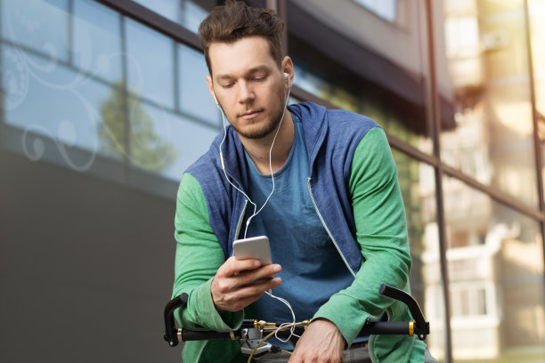 一张帅气的男人用智能手机骑自行车的照片图片下载