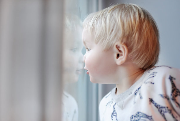一个蹒跚学步的小男孩从窗户往里看图片下载