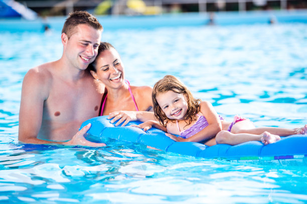 妈妈，爸爸和女儿在游泳池里。阳光明媚的夏天。图片下载