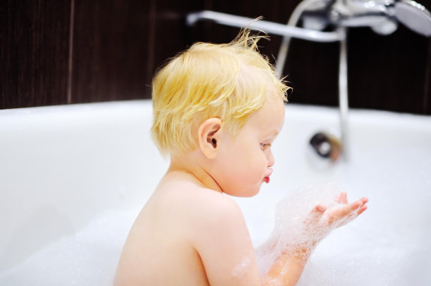金发的蹒跚学步的男孩在洗澡玩泡沫图片下载