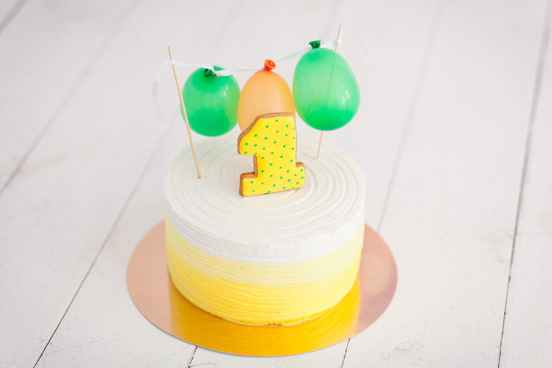 第一个生日打碎蛋糕。有一号和小气球的蛋糕。生日问候。黄色圆点饼干和奶油图片下载