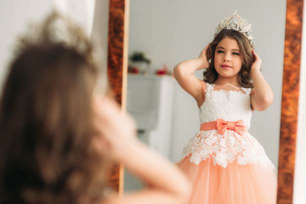 棕色头发的漂亮小女孩穿着桃红色的衣服。为摄影师摆姿势图片下载