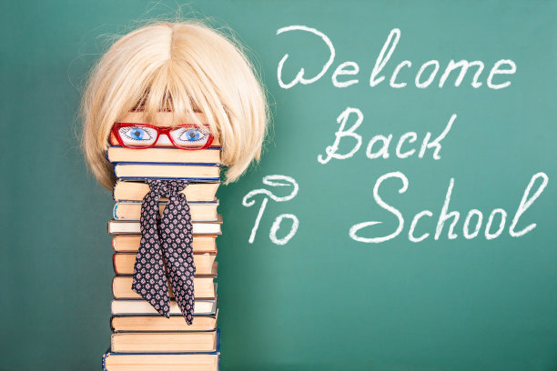 女老师在黑板前写着“欢迎回到学校”的标题图片下载