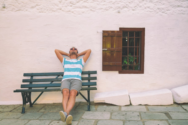 坐在长椅上的帅哥。享受和放松。图片下载