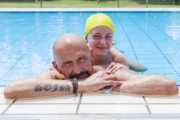 潮爸爸和女儿在泳池里放松图片下载