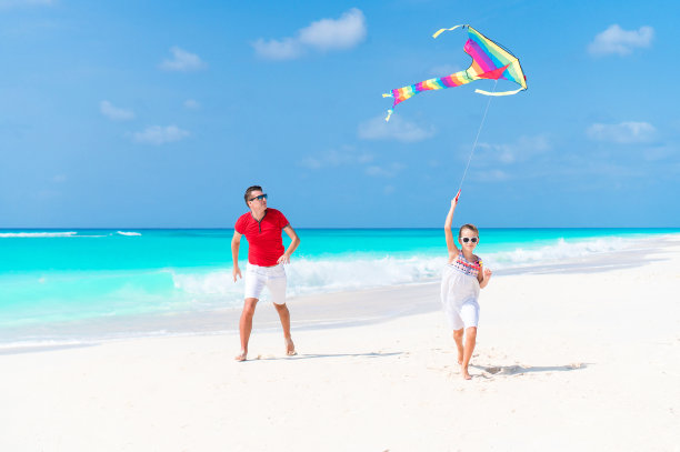 快乐的父亲和可爱的小女儿一起在热带海滩放风筝素材图片