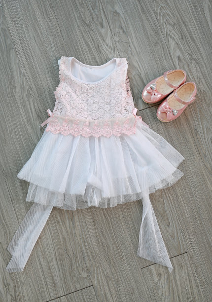 粉白色蕾丝裙与女孩的小鞋在一个木制的背景。图片下载