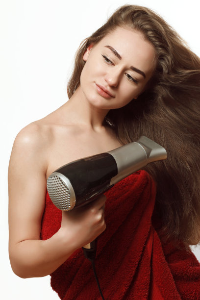 年轻的金发女人拿着吹风机图片下载
