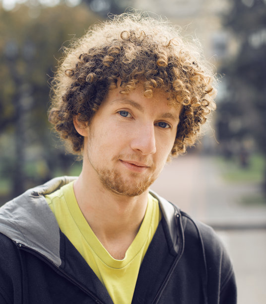 年轻卷毛男子肖像户外公园图片下载