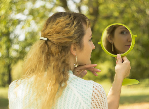 年轻漂亮的女孩在公园里照镜子图片下载
