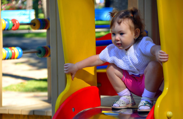 漂亮的女孩在操场上滑滑梯图片下载