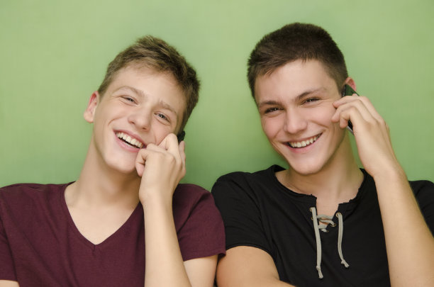 兄弟俩一边聊一边笑一边用智能手机图片下载