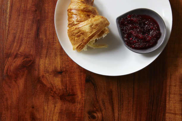 白盘子里放着牛角面包和果酱图片下载