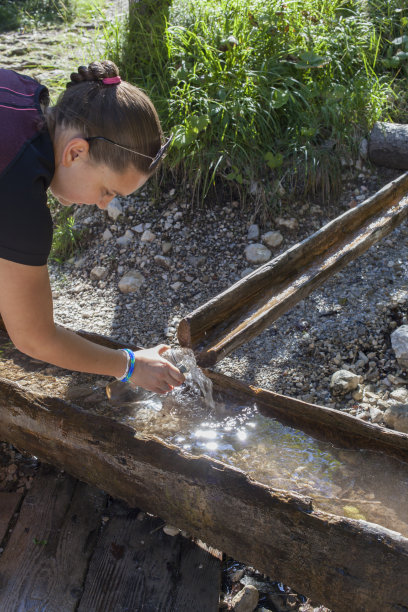年轻漂亮的女人从山涧里取水图片下载
